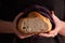 Woman in kitchen apron hold cuted frash bread in napkin in hand on black background