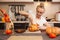 Woman on kitchen carves a pumpkin for Halloween in a room with autumn decor and a lamp house. Cosy home and preparing for