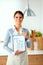 Woman in the kitchen at home, standing near desk with folder