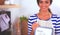 Woman in the kitchen at home, standing near desk with folder