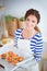 Woman in the kitchen at home, standing near desk with folder. Woman in the kitchen