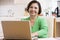 Woman in kitchen with laptop smiling