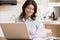 Woman in kitchen with laptop smiling