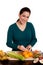 Woman in kitchen peeling orange