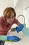 Woman on kitchen with rubber washing gloves cloth and detergent cleaning bored and tired