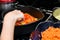 A woman in the kitchen stirs stewed peppers in a pan