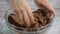 Woman kneading dough in the glass bowl.