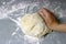 A woman kneads sweet yeast dough on the grey table