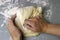 A woman kneads sweet yeast dough on the grey table