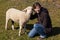 Woman kneeling beside a small lamb