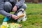 Woman kneels beside a pet rabbit in front of a feeding dish