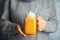 Woman in knitted sweater holding mason jar with pumpkin spice latte and whipped cream