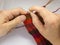 A woman knitting red woolen socks. Knitting close up on a white background. Hand crafts.