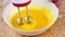 woman knocks broken eggs in a large white deep dish with a mixer on a wooden background strewn with