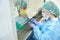 Woman laboratory assistant in overalls and gloves marks test tubes biomaterial