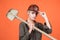 woman laborer in protective helmet and boilersuit hold shovel on orange background, construction