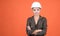 woman laborer in protective helmet and boilersuit on orange background, copy space, building