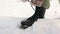 A woman laces up black winter boots on a street in a snowy forest. Women\\\'s hands tie shoelaces, winter shoes.