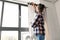 woman on ladder hanging curtains at home