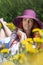Woman, lady with long red hair lying on a meadow with dandelions, h she is in a big hat