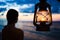 Woman in lantern shine looking to sea at sunset