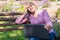 A woman with a laptop looks at a document in outdoors