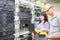 A woman with a laptop and a man with an oscillograph is working in the server room. A team of experts analyze data center data.