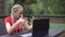 Woman with laptop outdoors talking on video call. A person works or studies remotely with a laptop