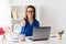 Woman with laptop showing thumbs up at office