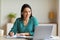 Woman At Laptop Taking Notes Learning Wearing Earbuds In Office