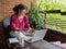 Woman with laptop working on the terrace at home