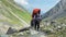 A woman with a large backpack walks along a mountain trail