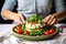 woman layering a piece of cauliflower steak in a salad