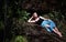 a woman laying down in the middle of the jungle, next to a waterfall