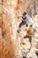 Woman lead climbing on natural cliff, guy belayer watching her