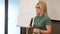 Woman leads a seminar for office workers using a microphone and a whiteboard