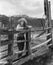 Woman leaning on wooden fence on ranch