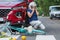 Woman leans against her red car and calls for help after causing an accident
