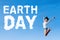 Woman leaps with Earth Day text