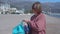 Woman with leash puts on backpack to walk away along beach