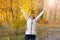 Woman with leaves in the autumn Park on a background of yellow blurred leaves