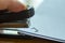 Woman left hand holding stapler and stapling white paper on wooden background, Problem Process, Close up & Macro shot, Selectiv