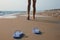 Woman left her beach slippers and walking barefoot on sandy seashore, closeup
