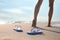 Woman left her beach slippers and walking barefoot on sandy seashore, closeup