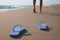 Woman left her beach slippers and walking barefoot on sandy seashore, closeup