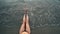 Woman legs and bare feet sitting on golden sand beach at sunset