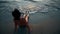 Woman legs and bare feet sitting on golden sand beach at sunset and looking at ocean water