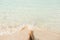 Woman legs barefoot on paradise beach. Clear transparent water splashing on feet