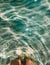 Woman legs barefoot at sea waves stones beach summer. top view above women feet.