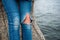 Woman legs in jeans torn on knee sits on pier against water